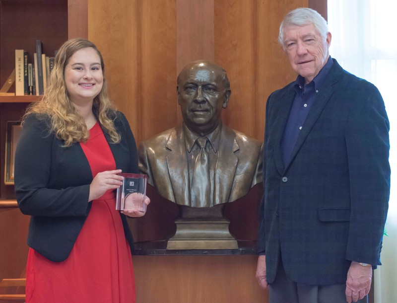 Bickley award winner Laura LePere, left, and Dr. William H. Rabel, John and Mary Louise Loftis Bickley Endowed Teaching Professor of Insurance, pose near a bust of Dr. John S. Bickley in the Insurance Hall of Fame Museum