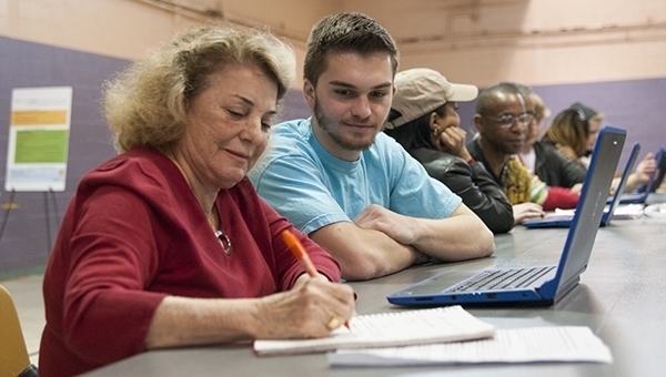 A LIFT volunteer teaches computer skills to a community member