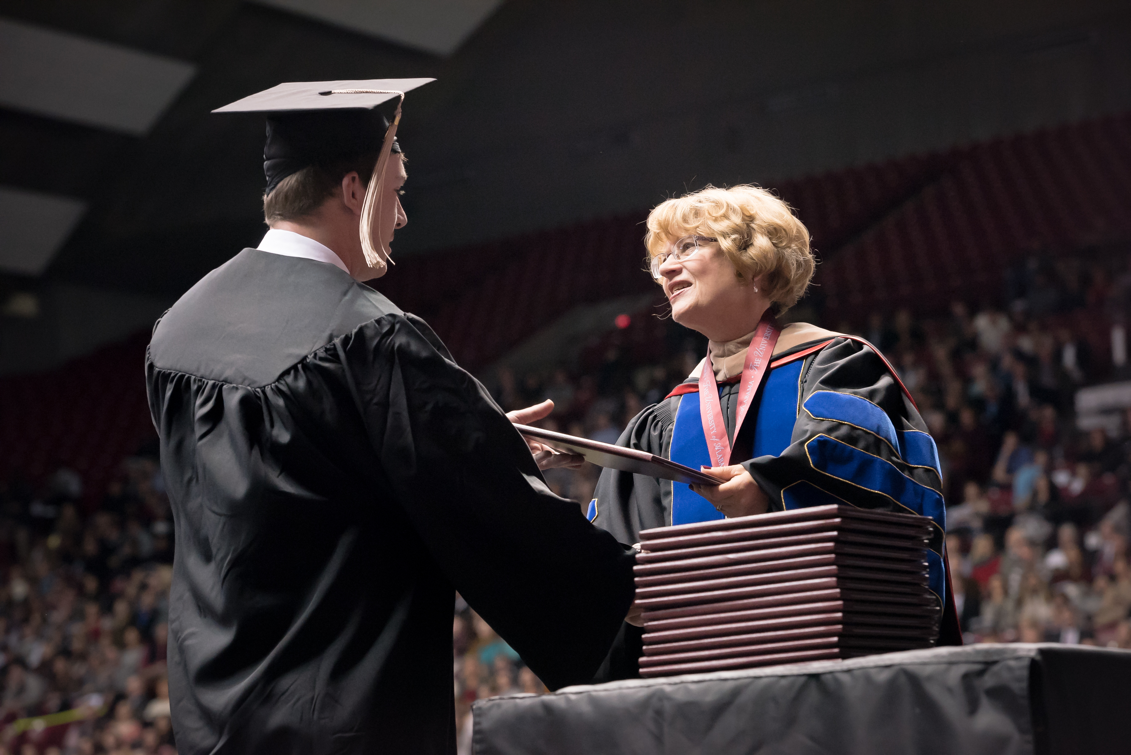 Dean Palan hands a degree to a student at graduation