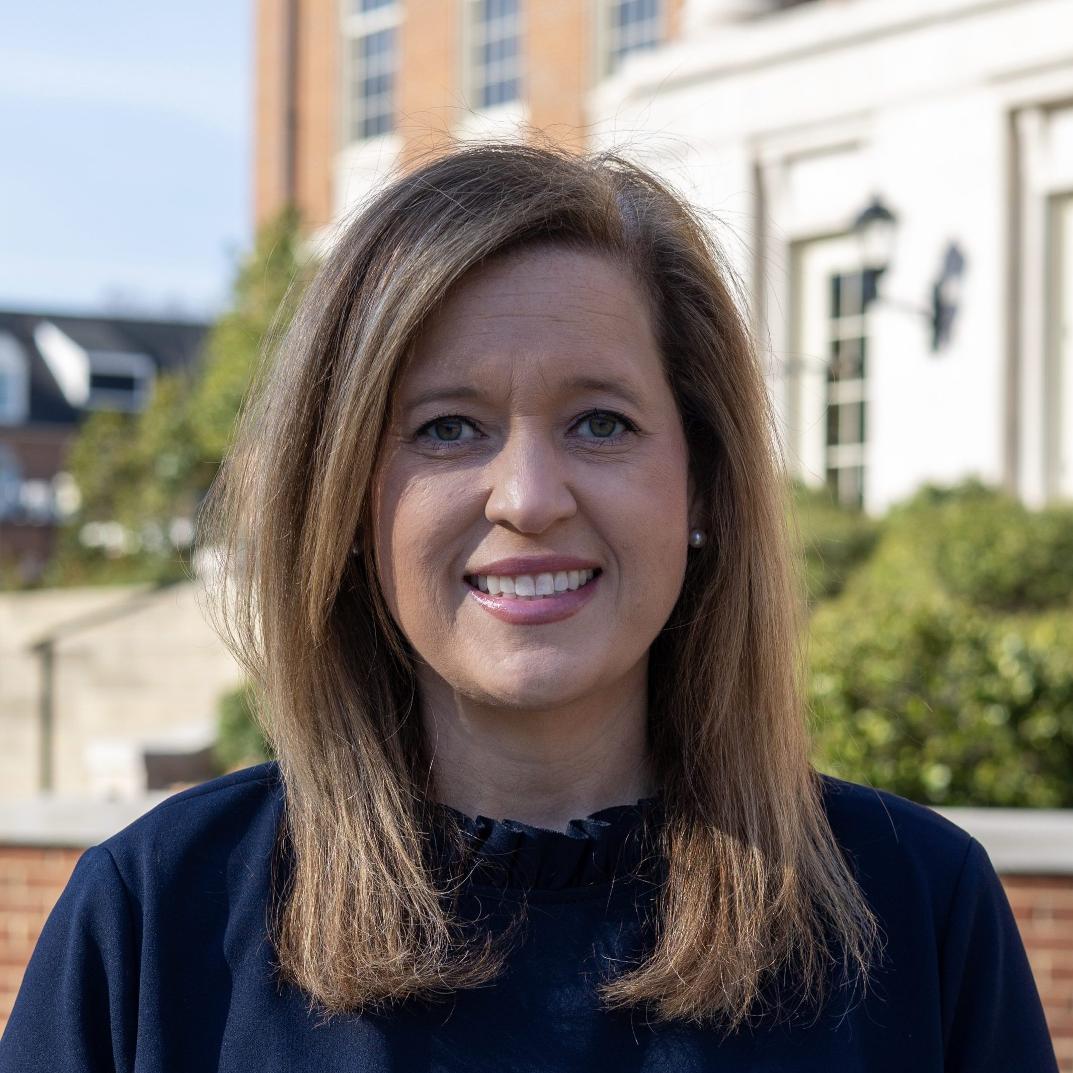 A headshot of a woman with buildings in the background.