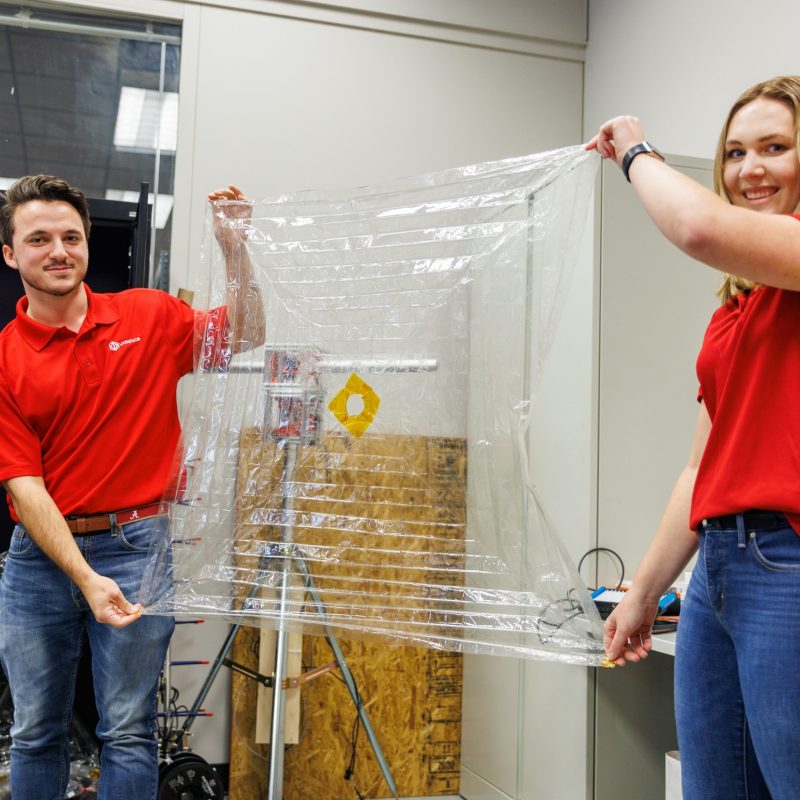 UASpace team members Chet Wiltshire and Abby Feeder hold an early version of the team’s drag sail, a technology that will quickly deorbit the satellite