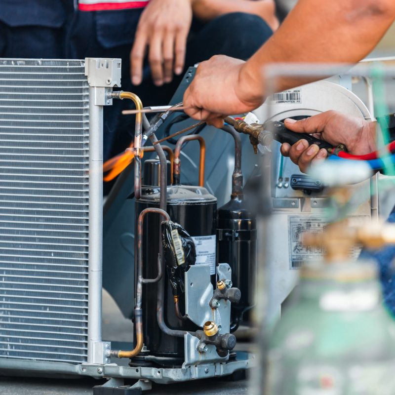 Close up of Air Conditioning Repair team use fuel gases and oxygen to weld or cut metals, Oxy-fuel welding and oxy-fuel cutting processes, repairman on the floor fixing air conditioning system