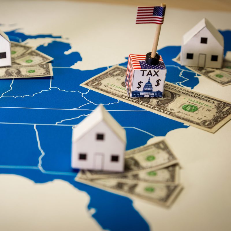 Family houses with dollar bills and central goverment tax over a US map.USA finance and economy concept related to the Tax Cuts and Jobs Act. approved by the Senate in December